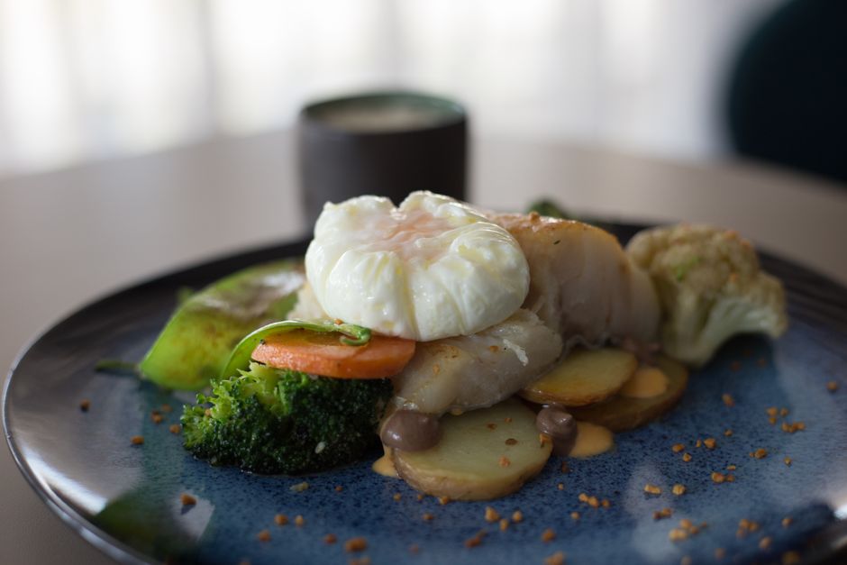 Delicious gourmet dish featuring a poached egg atop mixed vegetables on a blue plate.