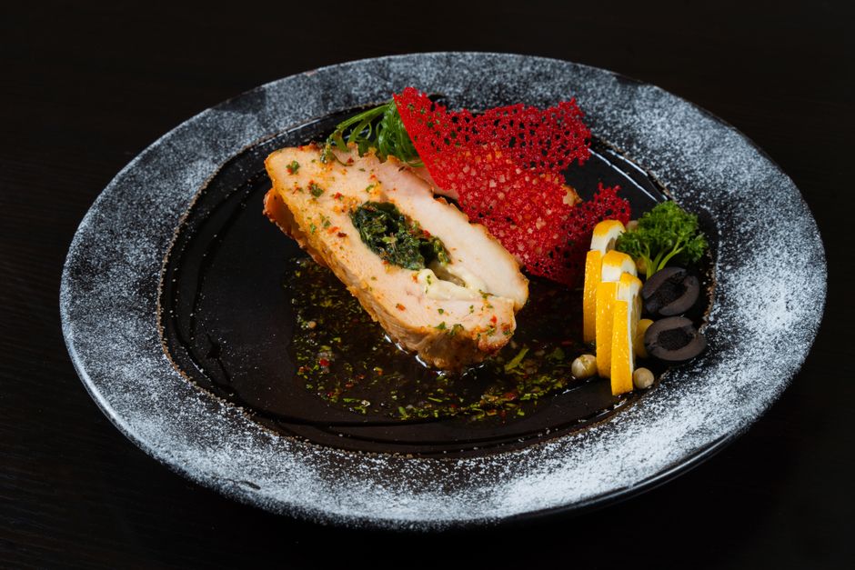 Delicious gourmet salmon dish with vibrant garnishes and creative plating on a dark plate.