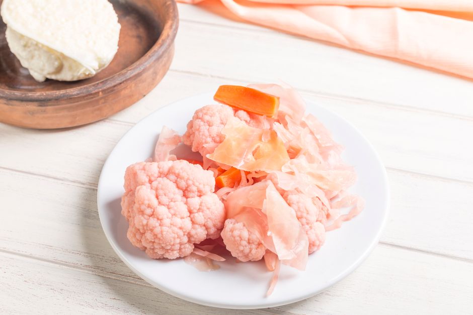 Pink pickled cauliflower and carrots on a white plate, perfect for culinary presentations.