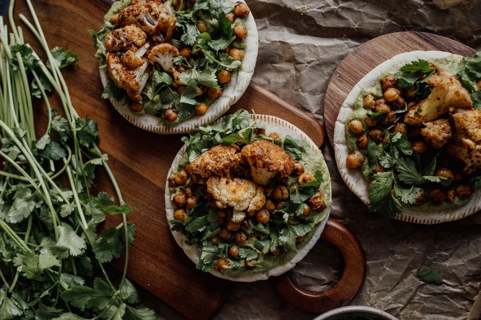 Delicious roasted cauliflower and chickpeas on pita, garnished with fresh cilantro, perfect for a vegan meal.