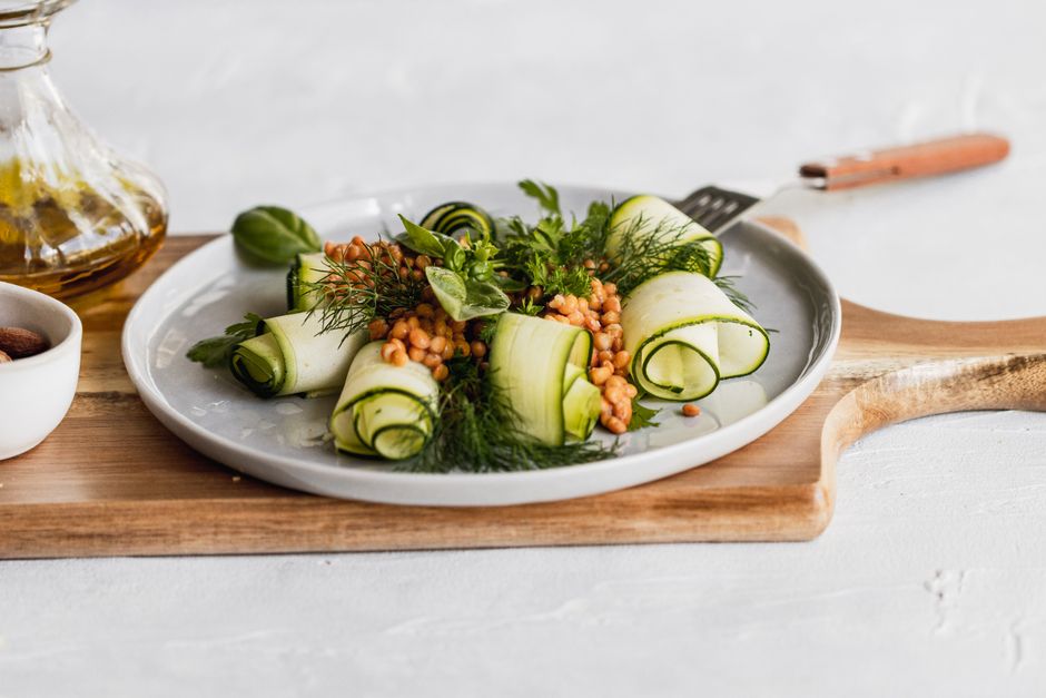 Delicious zucchini and lentil salad garnished with herbs on a wooden board, perfect for healthy eating.