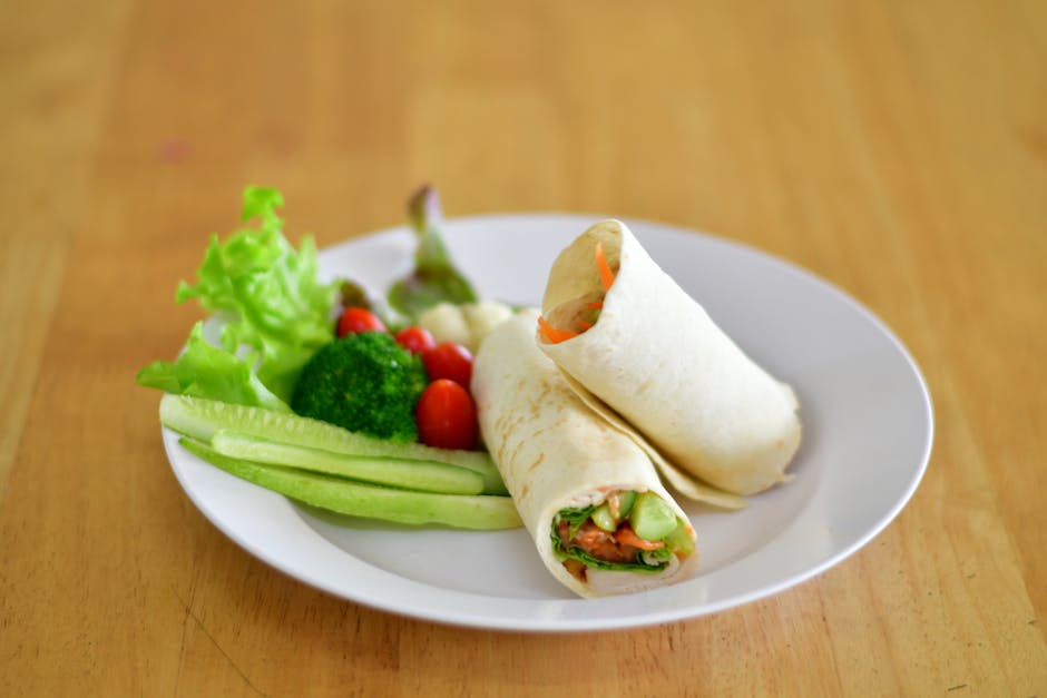Healthy wraps filled with vegetables served with fresh salad on a white plate.