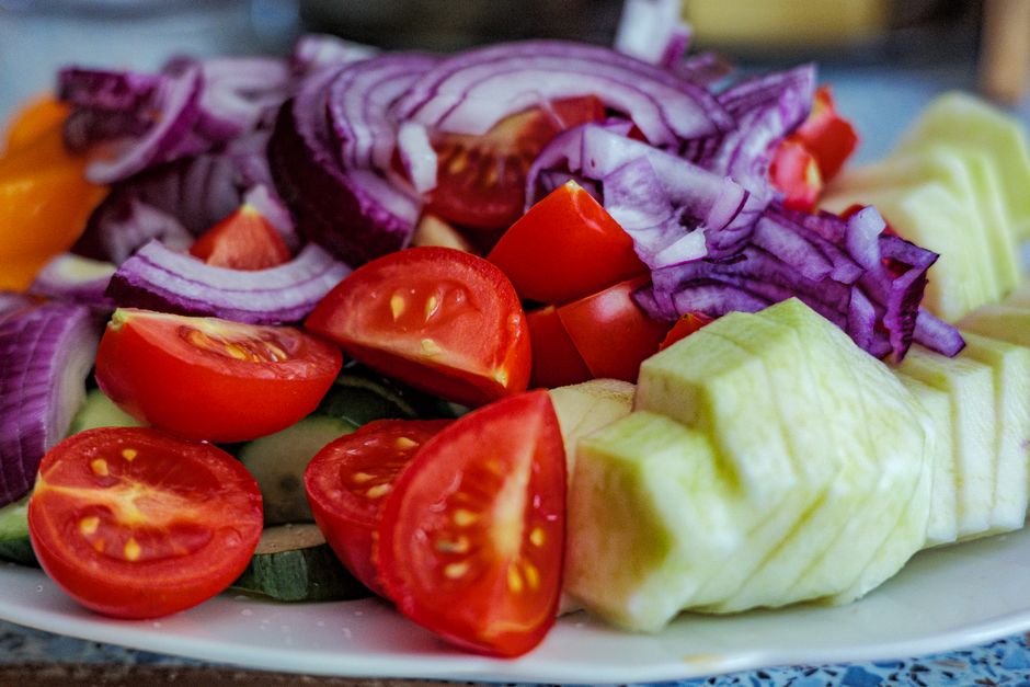 Colorful summer vegetable salad featuring tomatoes, cucumbers, and red onion slices on a plate.