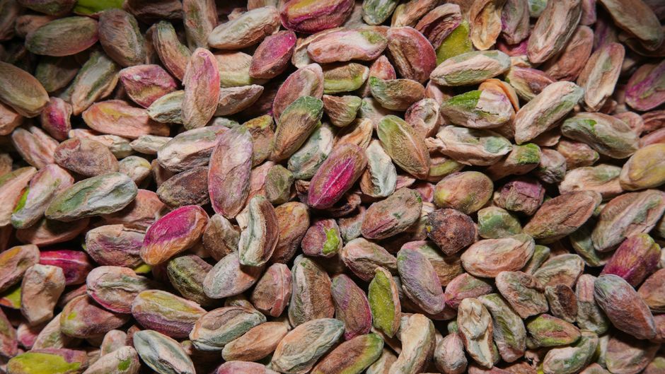 A high-resolution close-up of colorful unshelled pistachios, showcasing their natural texture and vibrant hues.