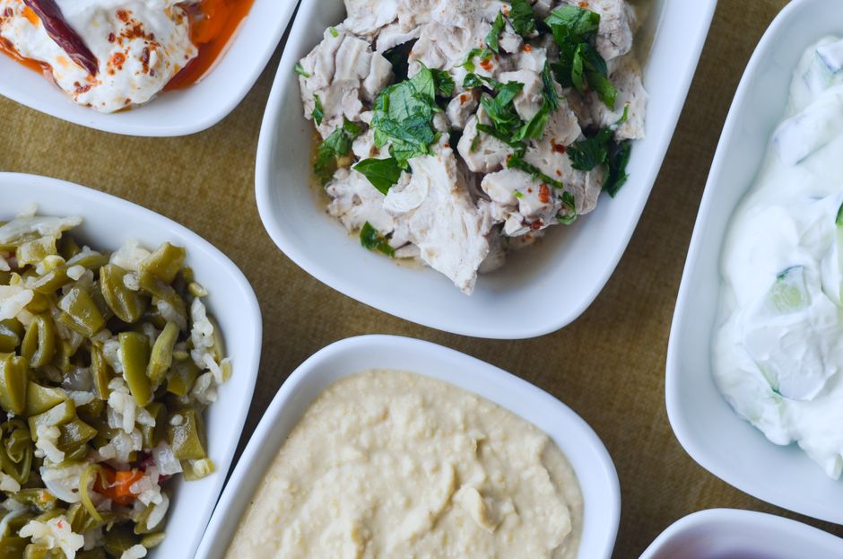 An appetizing assortment of Mediterranean dishes served in white bowls, showcasing diverse flavors.