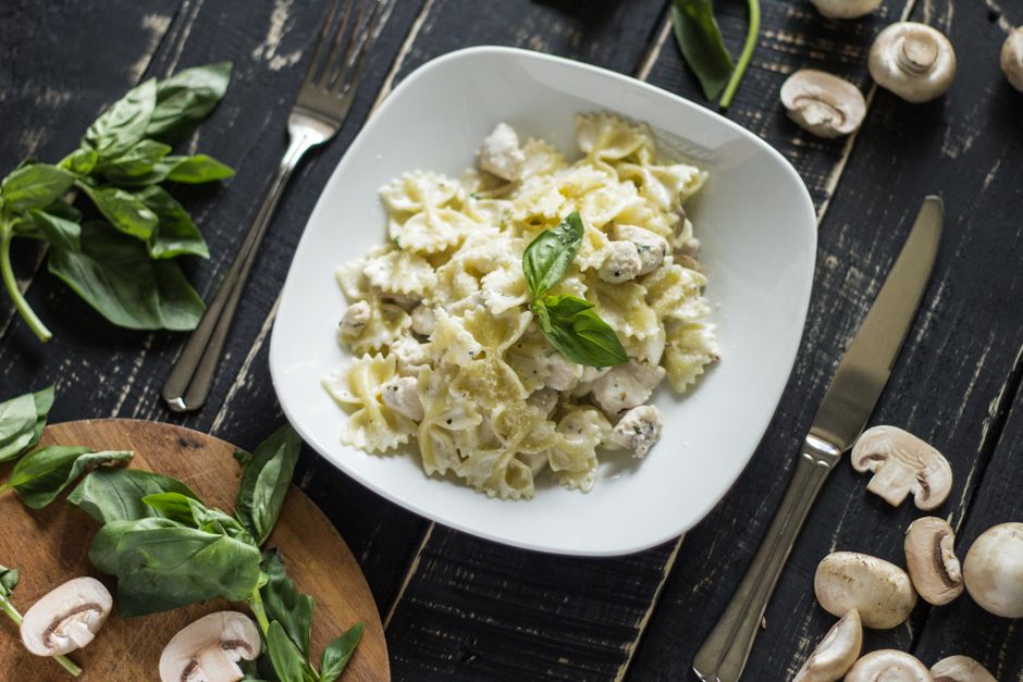 Delicious creamy bowtie pasta with mushrooms and basil, beautifully presented on a table.