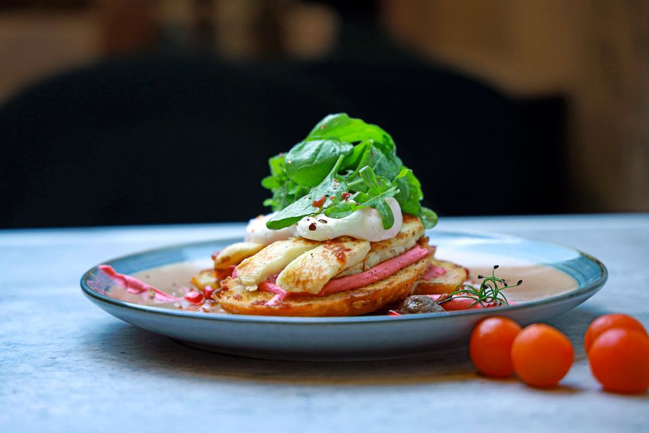 Delicious gourmet breakfast featuring halloumi, greens, and cherry tomatoes on a modern plate.