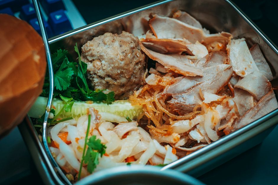 Delicious sliced meat and vegetables packed in a metal lunch box for a flavorful meal.
