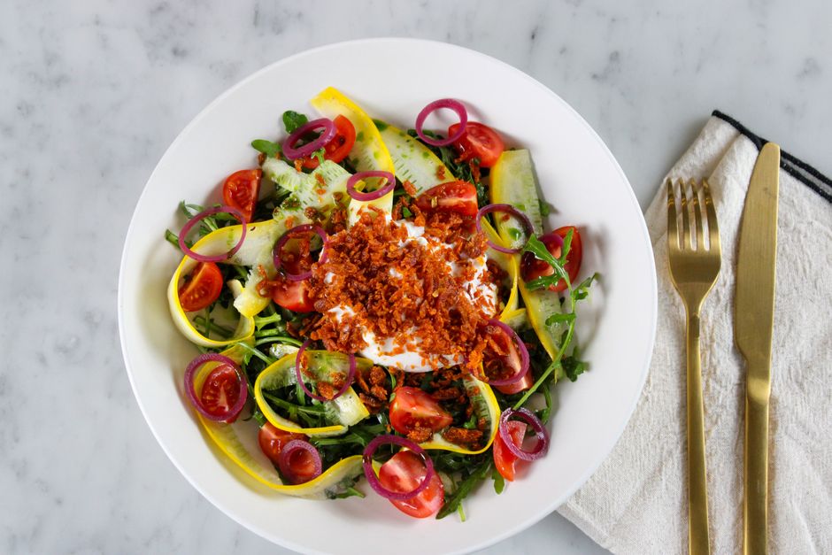 Colorful fresh salad with mixed vegetables and crispy toppings on a marble table.