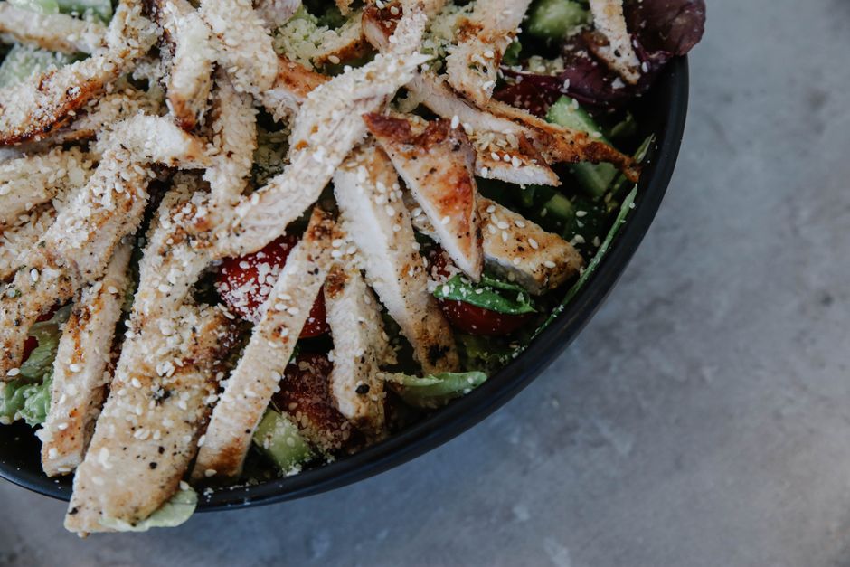 Delicious grilled chicken salad with fresh vegetables and sprinkled seeds.