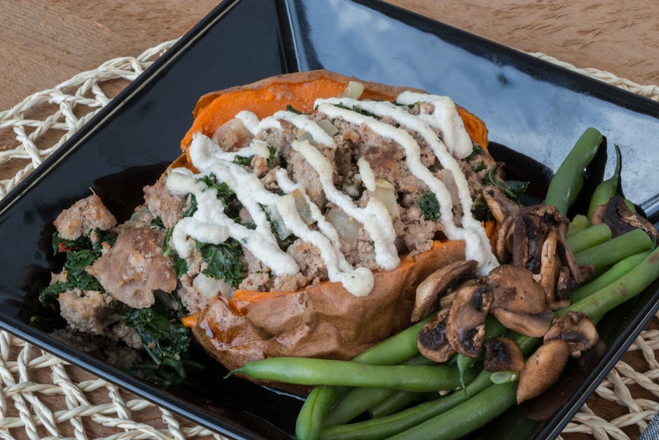 Close-up of stuffed sweet potato with beans and mushrooms on a black plate.