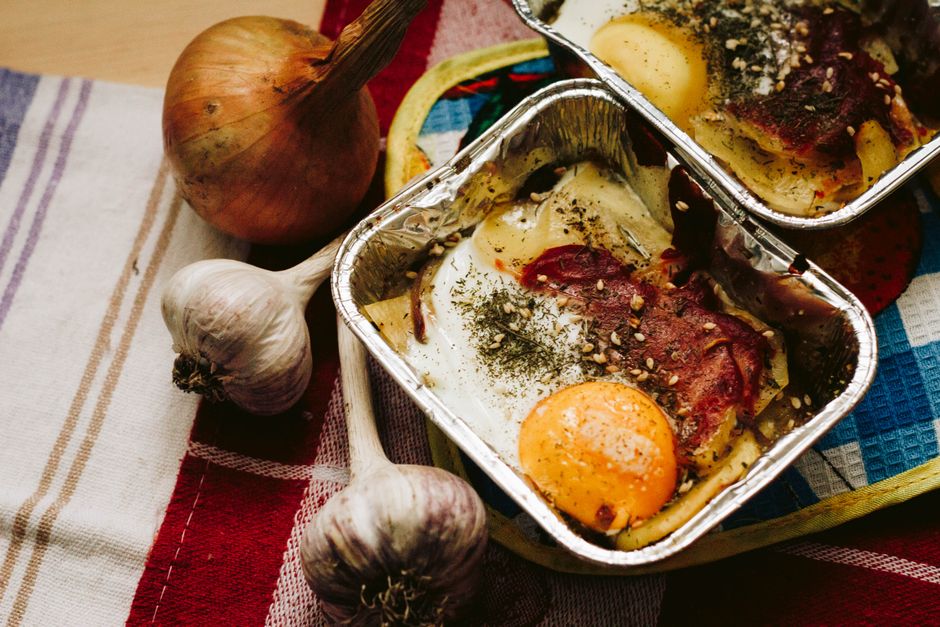 Close-up of a baked egg dish with vegetables and herbs in aluminum foil, perfect for a healthy meal.