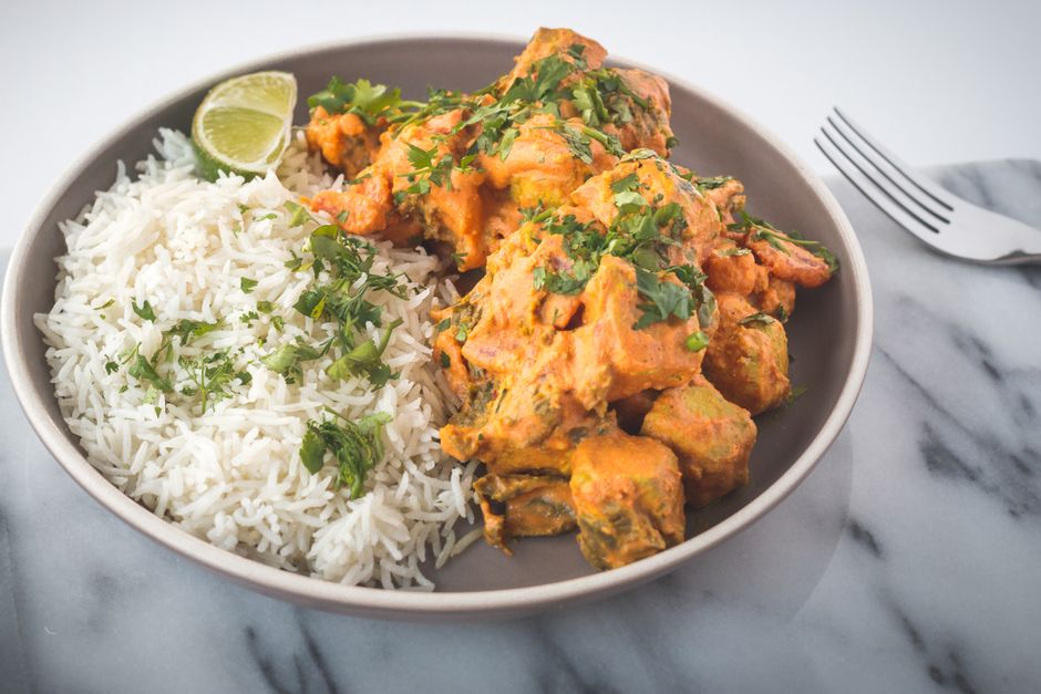A flavorful Indian curry served with jasmine rice and garnished with fresh herbs.