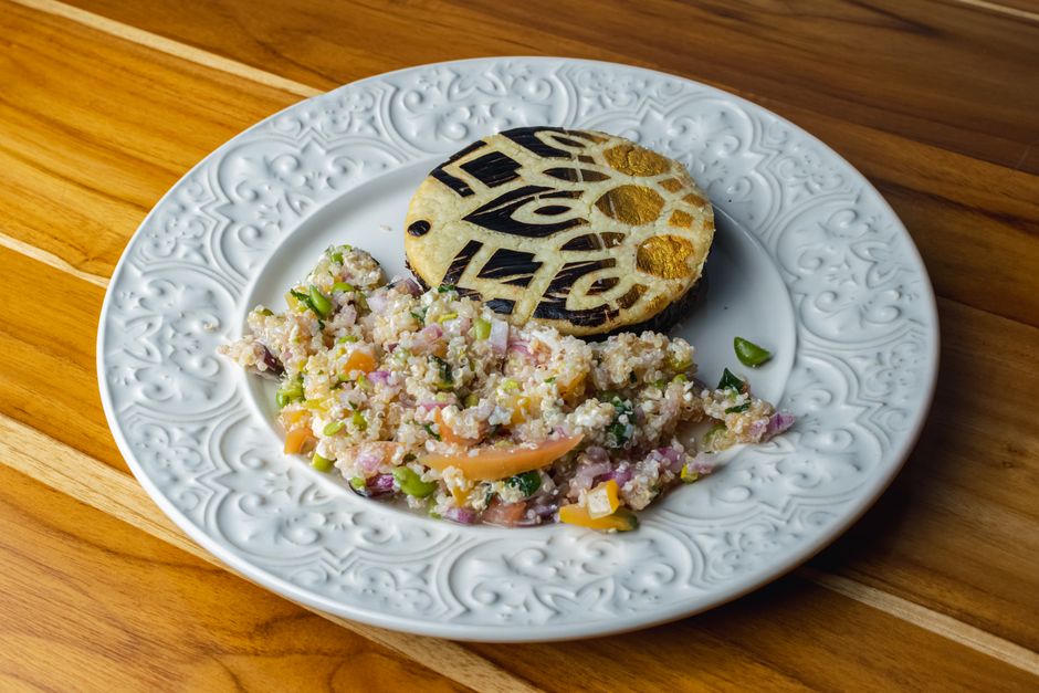Delicious quinoa salad with a beautifully decorated bread slice on a vintage plate.
