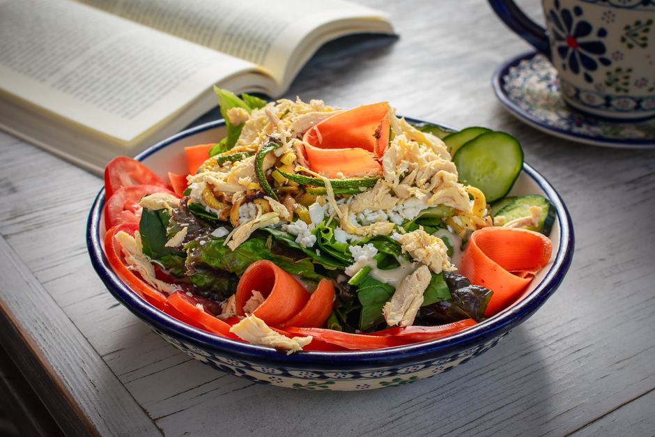 A vibrant chicken salad with fresh vegetables in a rustic setting, perfect for healthy eating.