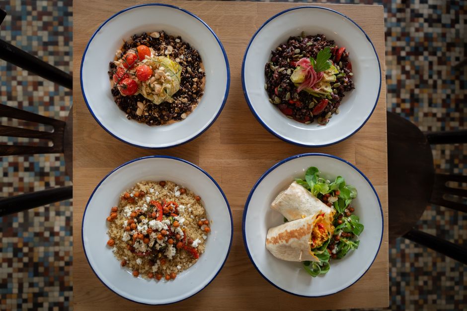 Top view of four healthy grain and vegetable bowls on a wooden table, perfect for nutritious meal ideas.