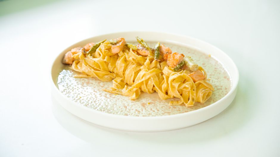 Savory pasta dish with shrimp and asparagus on a light plate.