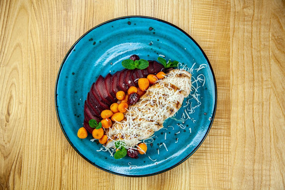 Delicious grilled chicken with vegetables and cheese on a vibrant blue plate.
