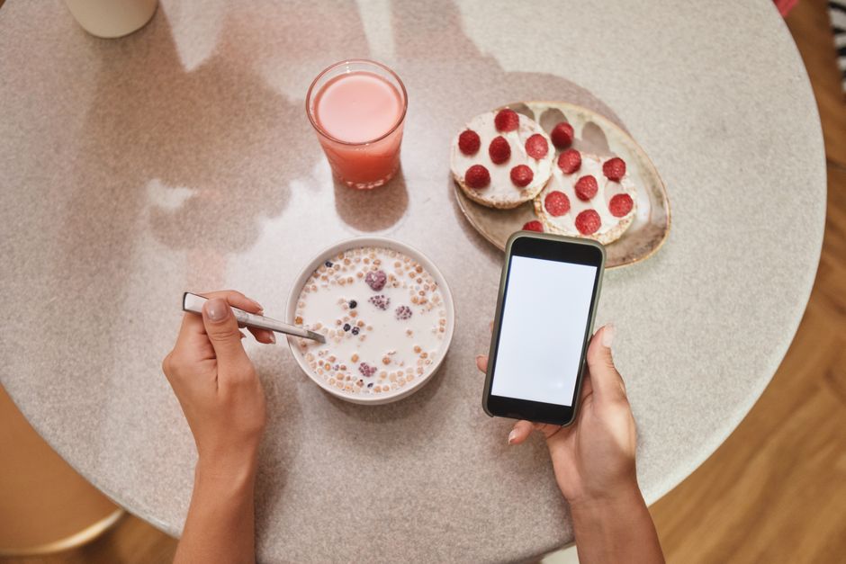 A cozy breakfast setup with cereal, toast, and a smartphone screen in view.