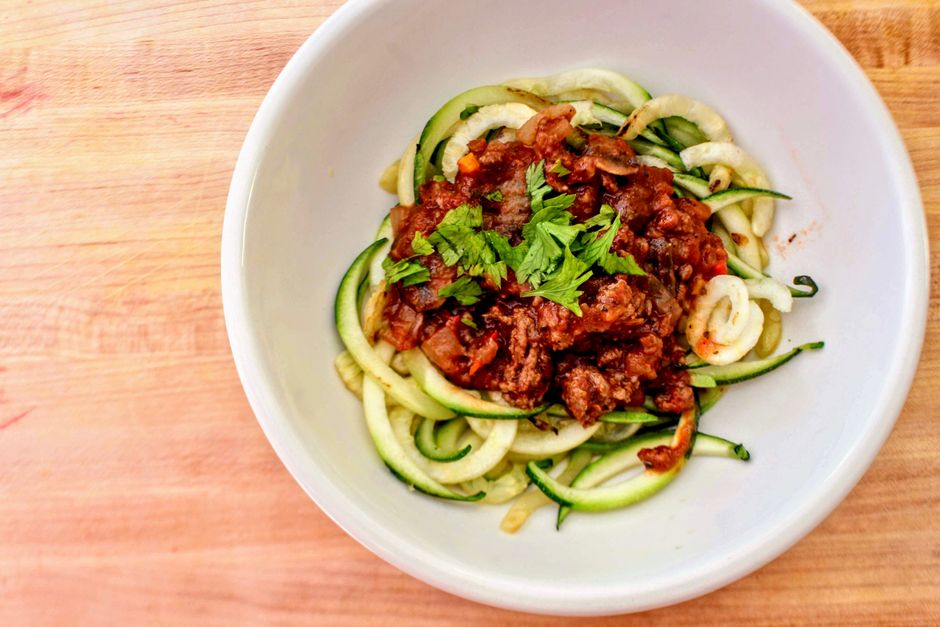 Zucchini noodles topped with rich tomato sauce and fresh herbs, ready to eat.